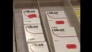 Mehrere Verpackungen des Medikaments "rökan" liegen in einer Schublade.  