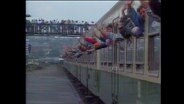 Menschen halten ihre Arme aus den Fenstern eines Zuges und winken (Archivbild).  