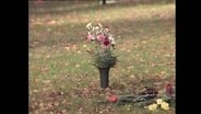 Ein Strauß Schnittblumen steht auf einer Friedhofswiese  