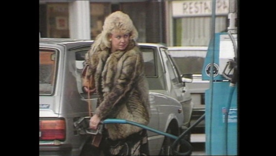 Eine Frau befüllt an einer Tankstelle ihr Auto mit Benzin  