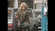 Eine Frau befüllt an einer Tankstelle ihr Auto mit Benzin  