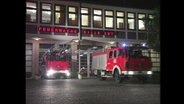 Zwei Feuerwehrautos fahren mit Blaulicht aus einer Feuerwache  