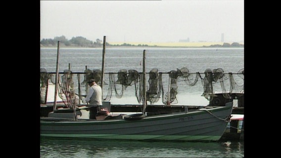 Ein Fischer liegt mit seinem Fischerboot an einem kleinen Ostseeanleger  