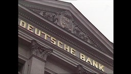 Der goldene Schriftzug "Deutsche Bank" auf einer Fassade.  