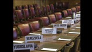 Ein langer Verhandlungstisch mit Tischkärtchen, auf denen "Yugoslavia, Venezuela, USA, UK" steht (Archivbild).  
