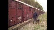 Ein Polizist mit Hund inspiziert einen Güterwagon (Archivbild).  