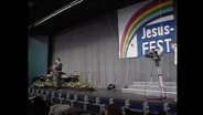 Eine Bühne mit dem Banner "Jesus-Fest", auf der eine Kamera steht (Archivbild).  