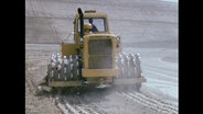 Ein gelber Traktor fährt über ein Feld (Archivbild).  