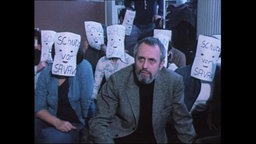 Demonstrierende mit Papier vor dem Gesicht, auf dem steht "Schutz von SAVAK" (Archivbild).  