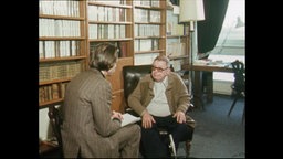 Sartre und ein Reporter sitzen vor einem Bücherregal (Archivbild).  