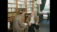 Sartre und ein Reporter sitzen vor einem Bücherregal (Archivbild).  