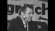 CSU Politiker Franz-Josef Strauß spircht an einem Podium  