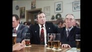 Mehrere Männer sitzen in einem Raum und trinken Bier  