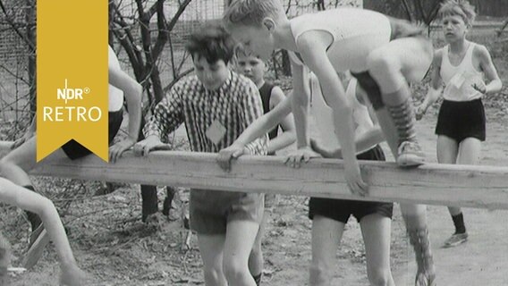 Kinder springen bei einem Hindernislauf bei Jugendsportveranstaltung in Wolfsburg über einen Balken (1965)  