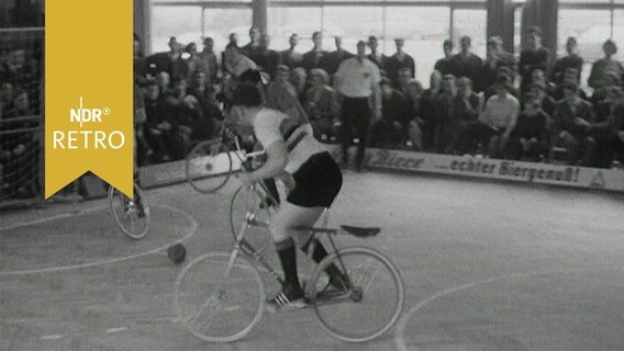Radballspieler in Aktion in einer gut gefüllten Turnhalle (1965)  