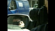 Ein Mann fotografiert heimlich aus einem Auto heraus  