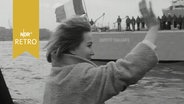 Frau winkt einem abfahrenden Marinekreuzer hinterher (1965)  