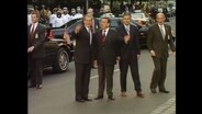 Der US-amerikanische Präsident George W. Bush und Bundeskanzler Gerhard Schröder stehen auf einer Straße  