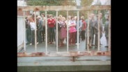 Zahlreiche Menschen stehen vor einem Tor  