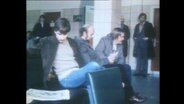 Männer sitzen auf dem Flur eines Arbeitsamtes (Archivbild)  