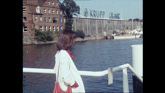 Eine Frau steht vor den Krupp-Werken in Kiel  