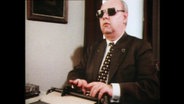 Ein Mann mit einer Sehbehinderung schreibt auf einer Schreibmaschine  