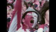 Ein Fussballfan im Stadion mit rot-weiß geschminktem Gesicht  