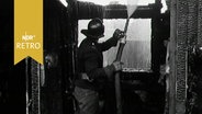 Feuerwehrmann spritzt nach oben in einem verkohlten Gebälk (1963)  
