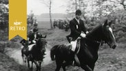 Reiter müssen beim Geländeritt durch einen Graben im Wald (1963)  