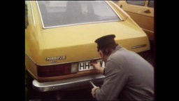 Ein Mann kniet vor einem gelben Auto  