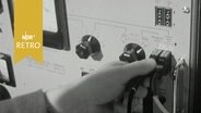 Eine Hand steckt einen Stecker in einer Telefonschaltstelle 1964  
