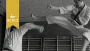 Zwei Karatekämpfer bei einer Vorführung im Training 1965, ein Tritt in hohem Sprung  