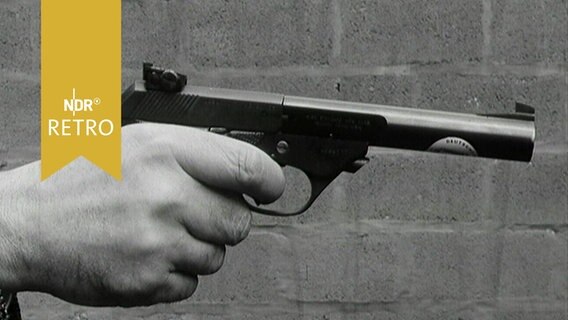 Hand hält eine Pistole, bereit zum Schuss (1965)  
