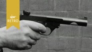 Hand hält eine Pistole, bereit zum Schuss (1965)  