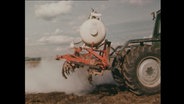 Ein Traktor düngt ein Feld  