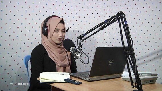 Die afghanische Journalistin Marzai Akbary sitzt vor einem Rundfunk-Mikrofon.  