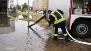 Ein Feuerwehrmann pumpt einen überschwemmten Tiefgarageneingang frei.  