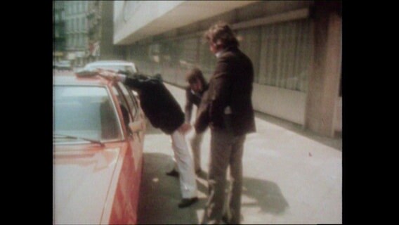 Fahnder der Polizei durchsuchen einen Mann (Archivbild)  