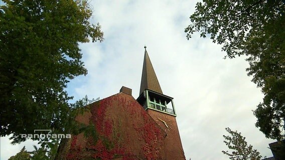 Ein Kirchturm vor bewölktem Himmel  