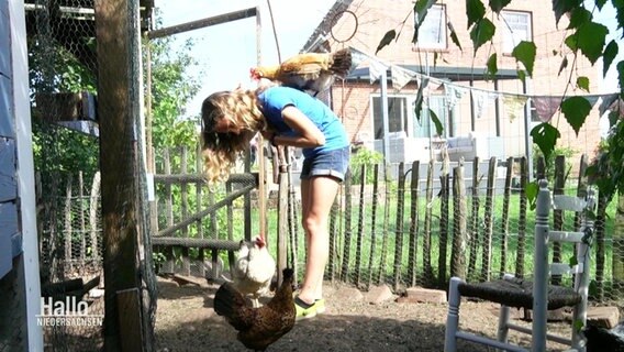 Ein junges Mädchen, das mit Hühnern spielt.  