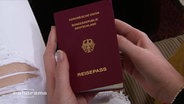 Eine junge Frau hält ihren deutschen Reisepass in den Händen  