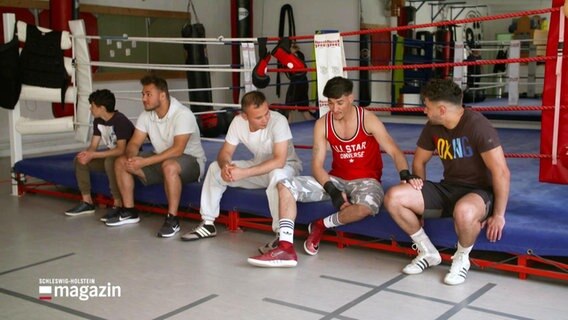 Fünf Vereinsmitglieder vom Kieler Box-Club sitzten sich unterhaltend am Boxringrand.  