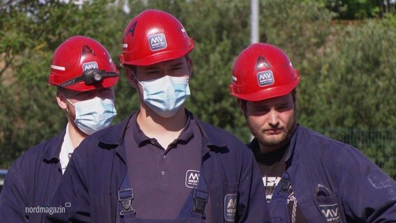 MV-Werftler auf einer Protestveranstaltung, sie tragen Arbeitskleidung und rote Schutzhelme.  