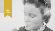 Stewardess in Pause zündet sich eine Zigarette an (1958)  
