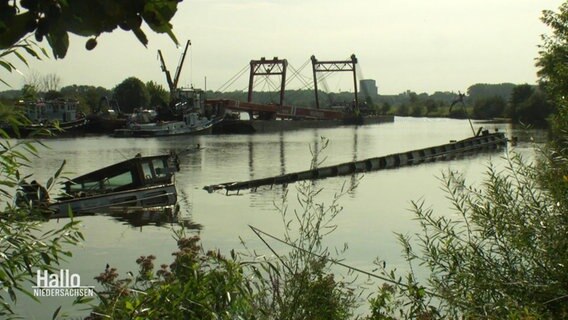 Blick auf einen Weserlauf. Aus der Mitte des Flusses ragen Teile eines Schiffes empor, dass unter gegangen ist.  