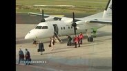 Fluggäste steigen aus einer Propellermaschine  