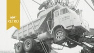 Ein Muldenkipper hängt am Kran bei der Verladung im Hafen von Bremen (1964)  