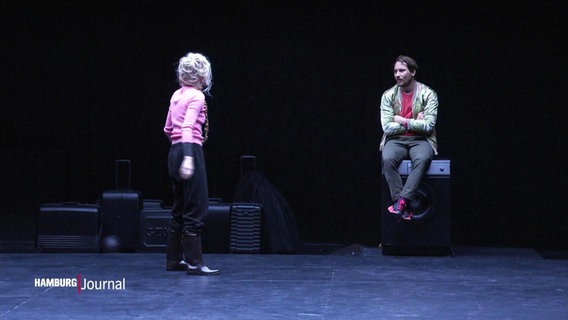 Eine Schauspielerin und ein Schauspiler sind auf der Bühne und sehen sich an.  