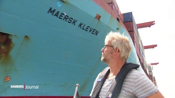 Holger Brauns segelt vor einem Containerschiff entlang.  