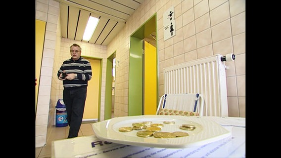 Ein Teller mit Münzen vor einer Toilette © NDR 